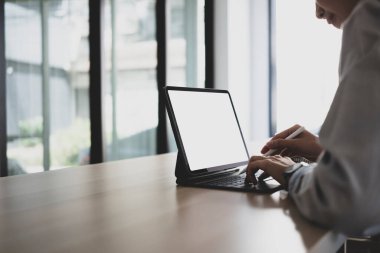 İşkadını ahşap ofis masasında bilgisayar tableti kullanırken görüntüyü kapat.