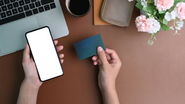 Çevrimiçi bankacılık hizmetleri veya online alışveriş için akıllı telefon kullanan ve kredi kartı tutan kadınların üst görüşü.