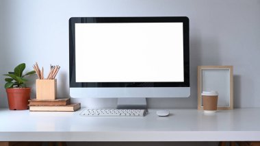 Bilgisayarı, tesisi, kitapları ve kahve fincanı olan ofis masası..