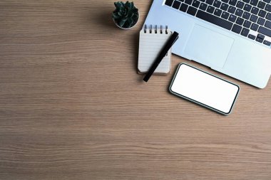 Bilgisayarın üst görüntüsü, akıllı telefon ve ahşap arka plandaki defter.