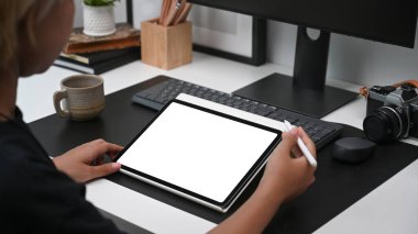 Modern ofiste dijital tabloyla çalışan genç kadın grafik tasarımcısının omuz üstü görüntüsü.