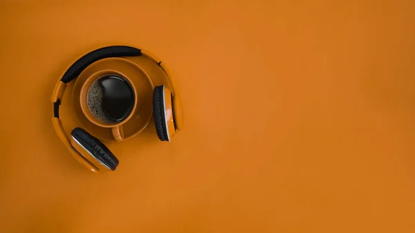 Mock up head phone, coffee cup and copy space on orange background.