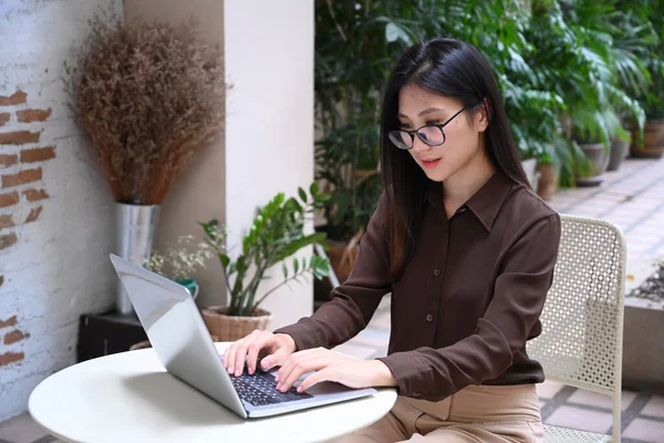 Młoda Azjatka Okularach Koncentruje Się Pracując Laptopie Podczas Siedzenia Świeżym — Zdjęcie stockowe