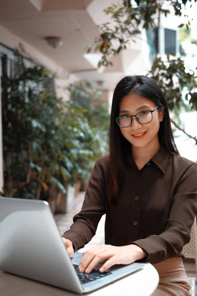 一个微笑的女商人坐在室外用笔记本电脑工作的画像 — 图库照片