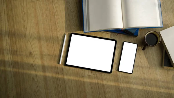 Empty screen tablet and smartphone with books on wooden floor.