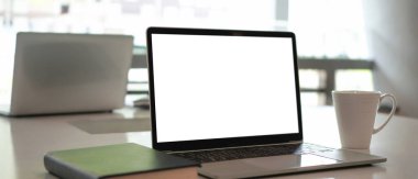 Toplantı odasındaki ahşap masada bilgisayar, defter ve kahve fincanının görüntüsünü kapat..