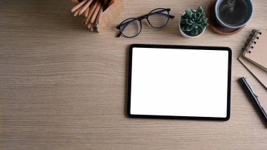 Boş ekranlı yatay dijital tabletin üst görüntüsü, kahve bardakları ve ahşap arka planda sulu bitkiler.