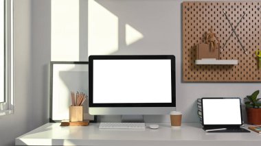 Beyaz masa üzerinde bilgisayar, dijital tablet ve ofis malzemeleri ile rahat çalışma alanı.