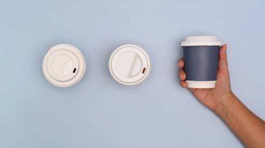 Kağıt kahve fincanı ve beyaz arka planda el, kapat..