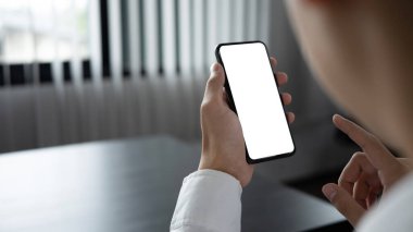 Boş ekran ile mobil cep telefonu tutan işadamının omzunun üzerinden bak.