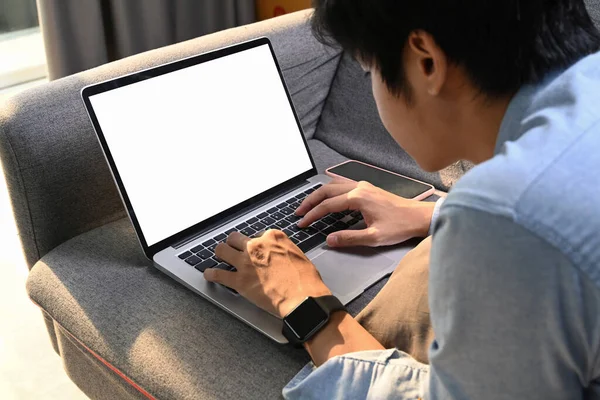 若いアジア人男性横たわっ快適なソファに自宅とブラウジングインターネット上のラップトップコンピュータ — ストック写真
