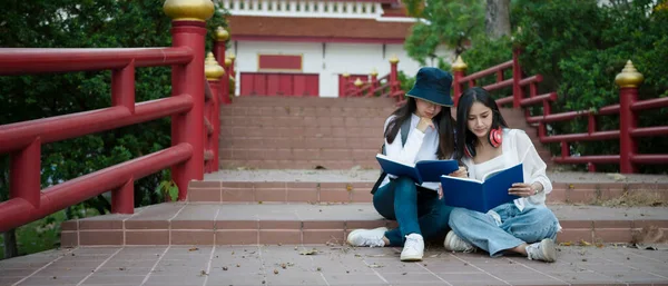 Dwóch Azjatyckich Studentów Czyta Książkę Siedząc Schodach Kampusie Uniwersyteckim — Zdjęcie stockowe