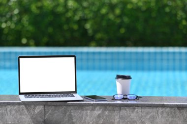 Boş ekranlı bilgisayar, yüzme havuzunun yanında kahve fincanı ve bardaklar..