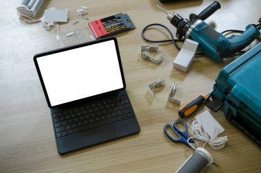 Above view of computer tablet with empty screen and construction tools wooden floor.