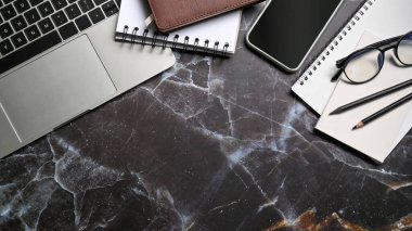 Bilgisayar dizüstü bilgisayar, akıllı telefon ve mermer masada not defterleri. Çalışma Alanı.