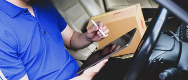 Minibüste otururken teslimatçı dijital tablette listeyi kontrol ediyor. 