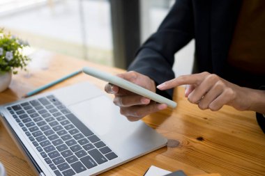 Ofiste otururken akıllı telefondan daktilo eden iş kadınının yakın görüntüsü.