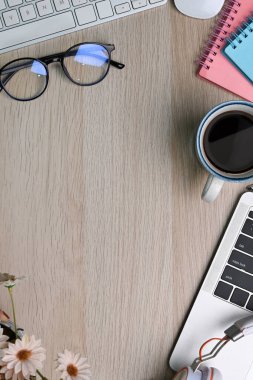 Bardakları, dizüstü bilgisayarı, kahve fincanı ve defteriyle ahşap masa üzerinde basit bir iş yeri..