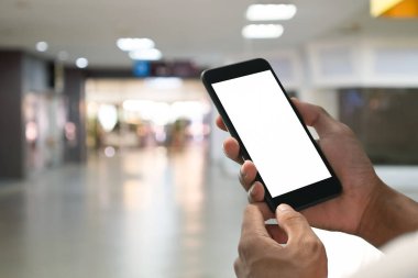 Arka planda bulanık alışveriş merkezi olan akıllı telefonu tutan adamı kapat..