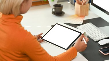 Yaratıcı ofiste otururken dijital tablo kullanan kadın tasarımcının arka görünümü.