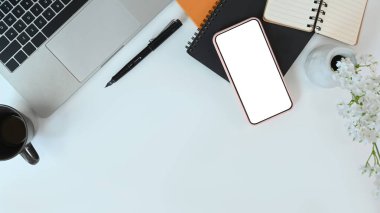 Dizüstü bilgisayarı, akıllı telefonu, defteri ve kahve fincanı olan üst düzey ofis çalışma alanı.