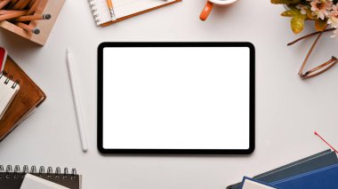 Dijital tablet ve ofis malzemeleriyle beyaz masa üzerinde yaratıcı tasarımcı çalışma alanının en üst görünümü