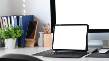 Boş ekranlı bilgisayar tableti ve ofis masasında ofis malzemeleri.