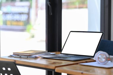 Bilgisayar dizüstü bilgisayar, kulaklık, kitaplar ve kağıt işleri ahşap masada..