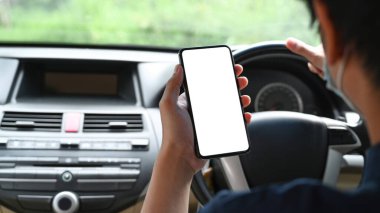 Araba sürerken cep telefonu kullanan genç adam dikiz görüntüsü.