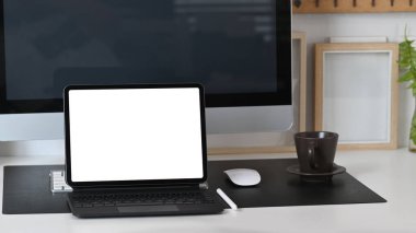 Mock up digital tablet with empty screen, computer and coffee cup on white office desk.