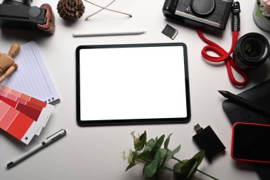 Beyaz masadaki dijital tablet ve kamera aksesuarlarını düzenle.