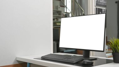 Simple workspace with computer and house plant on white table.