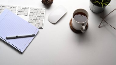 Simple workspace with, notebook, coffee cup, plant, keyboard on white desk. clipart