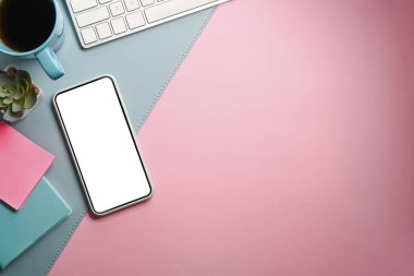 Üst görünüm cep telefonu, defter, kahve fincanı reklam klavyesi, pembe ve mavi arka plan..