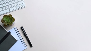 Üzerinde klavye, defter ve kaktüs olan beyaz ofis masası.