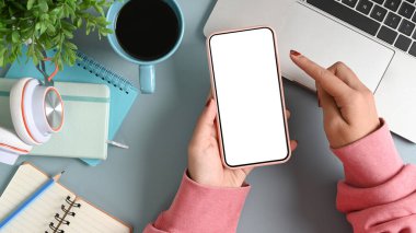 Ofis masasında boş ekranlı cep telefonu tutan şık bir kadın..