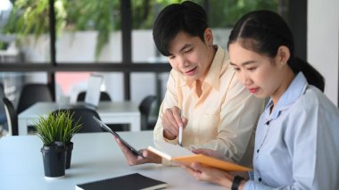 Two young business people discussing new project together in modern office room.