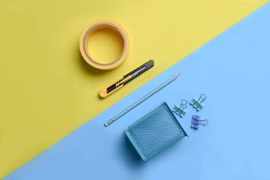 Yapıştırıcı bant, kesici bıçak ve iki renkli sarı ve mavi arka planda kalem tutacağı..