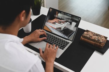 Çevrimiçi alışveriş için dizüstü bilgisayar kullanan genç adam.