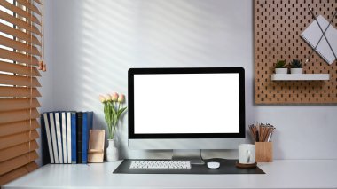 Neat and ordered workspace with computer, books and office supplies on white table.