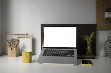 Bilgisayar laptopu, kahve fincanı, ev bitkisi, akıllı telefon ve kalem tutucuyu beyaz masaya yerleştir..