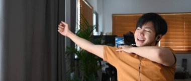 Mutlu genç adam evde online çalışırken vücudunu esnetiyor..