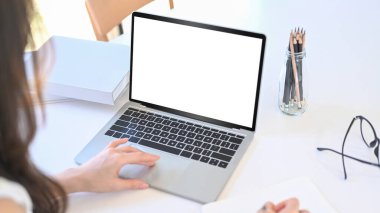 Beyaz ofis masasında dizüstü bilgisayarla çalışan bir kadının omzunu kapat..