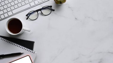 Mermer zemin üzerinde defter, bardak, kahve fincanı ve cep telefonu olan basit çalışma alanı.