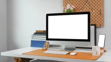 Bilgisayarlı modern çalışma alanı, akıllı telefon, kahve fincanı, kitaplar ve ofis malzemeleri beyaz masada..