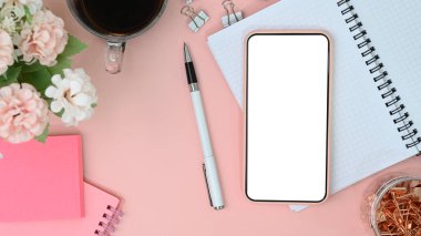 Mock up mobile phone with white screen on female workspace.