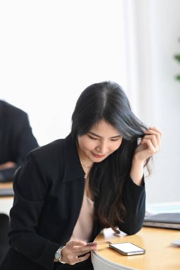 Ofiste kahve molası sırasında cep telefonu kullanan Asyalı kadın..