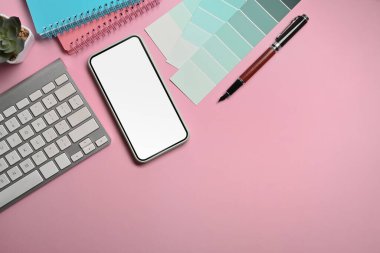 Grafik tasarımcı çalışma alanı üzerinde akıllı telefon, defter ve klavye.
