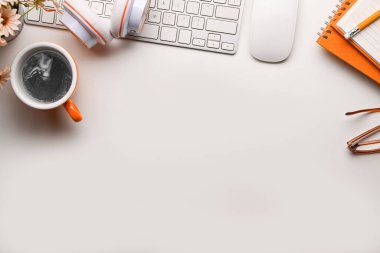 Kahve fincanı, kulaklık, defterler ve klavyeli modern çalışma alanı beyaz masanın üzerinde..