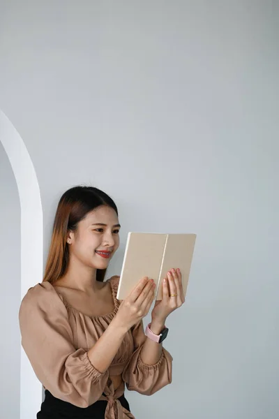 Portrait of businesswoman reading information on notebook while sitting in office.
